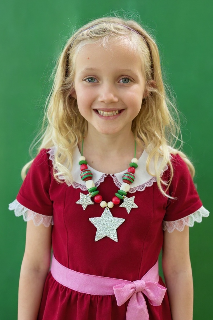 Young girl wearing a red dress with white lace trim and a star necklace against a green background